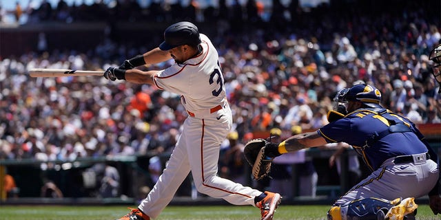 San Francisco Giants' LaMonte Wade Jr., left, hits a three-run home run in front of Milwaukee Brewers catcher Omar Narvaez during the third inning of a baseball game in San Francisco, Sunday, July 17, 2022. 