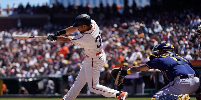 San Francisco Giants' LaMonte Wade Jr., left, hits a three-run home run in front of Milwaukee Brewers catcher Omar Narvaez during the third inning of a baseball game in San Francisco, Sunday, July 17, 2022.