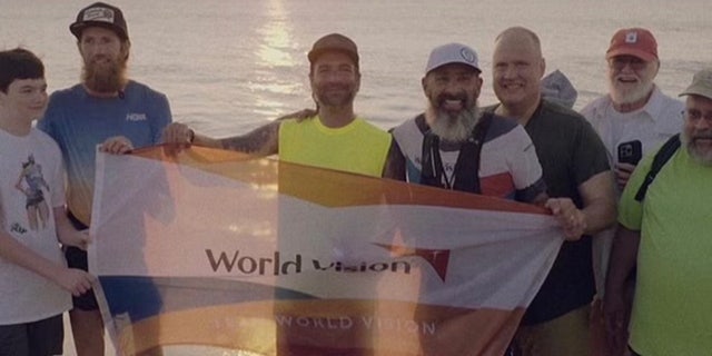 Mike Wardian and others hoist a World Vision banner.  