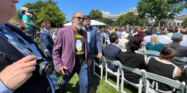 Manuel Oliver, the father of a child who died during the Parkland, Fla., school shooting, is escorted out of an event on the White House South Lawn after interrupting President Biden's remarks on gun control. 