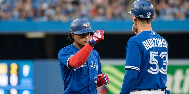 Blue Jays' Santiago Espinal celebrates with first base coach Mark Budzinski after hitting a single against the Boston Red Sox on June 29, 2022, in Toronto.