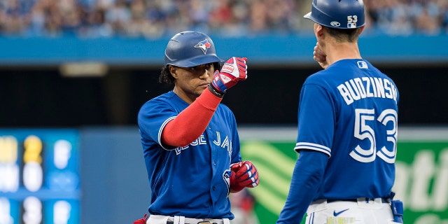 Blue Jays' Santiago Espinal celebrates with first base coach Mark Budzinski after hitting a single against the Boston Red Sox on June 29, 2022, in Toronto.