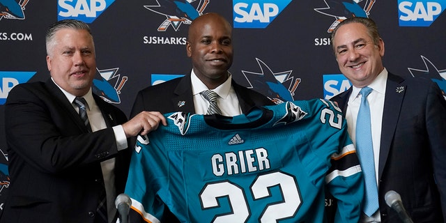 Mike Grier, middle, poses for photos as he is introduced as the new general manager of the San Jose Sharks at a news conference in San Jose, Calif., Tuesday between assistant general manager Joe Will, left, and President Jonathan Beecher. , July 5, 2022.