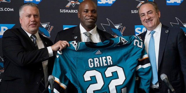 Mike Grier, middle, poses for photos as he is introduced as the new general manager of the San Jose Sharks at a news conference in San Jose, Calif., Tuesday between assistant general manager Joe Will, left, and President Jonathan Beecher. , July 5, 2022.