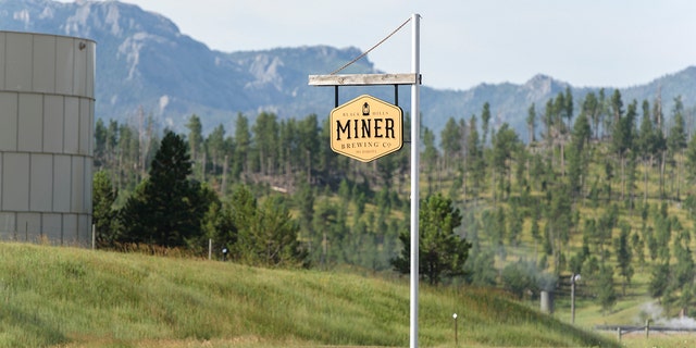 A Miner Brewing sign hangs in front of the Rocky Mountains in Hill City, S.D.