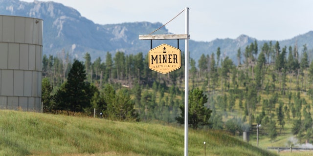 A Miner Brewing sign hangs in front of the Rocky Mountains in Hill City, S.D.