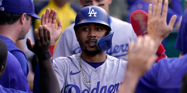 Los Angeles Dodgers' Mookie Betts is congratulated by teammates in the dugout after scoring on single by Freddie Freeman during the first inning of a baseball game against the Los Angeles Angels Friday, July 15, 2022, in Anaheim, Calif. 