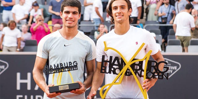 Italy's Lorenzo Musetti, right, holds the trophy after beating Spain's Carlos Alcaraz, left, at the Hamburg tennis tournament, Germany, Sunday July 24, 2022.  