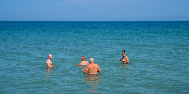 People stand in the Atlantic Ocean at low tide July 23, 2022, at Nauset Beach, Cape Cod, in Orleans, Massachusetts.