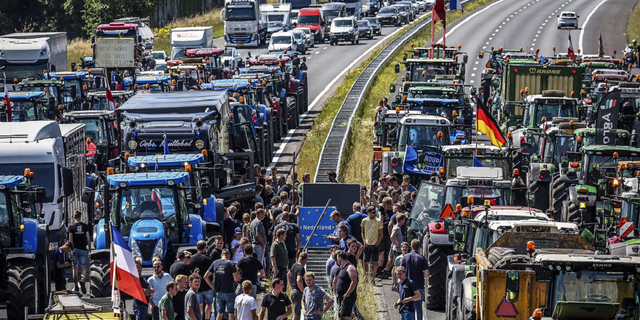 Farmers gather with their vehicles next to a Germany/Netherlands border sign during a protest on the A1 highway, near Rijssen, on June 29, against the Dutch government's nitrogen plans.