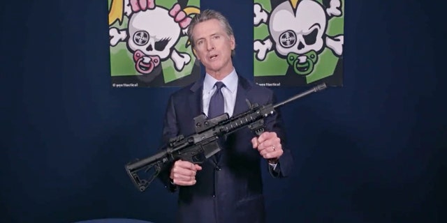 Kaliforniese goewerneur. Newsom holds an assault-style rifle while announcing new gun legislation.