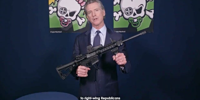 Kaliforniese goewerneur. Newsom holds an assault-style rifle while announcing new gun legislation.