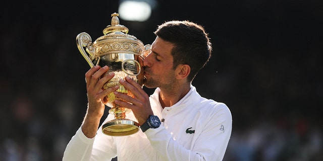 Serbia's Novak Djokovic kisses his trophy after defeating Australia's Nick Kyrgios in the Wimbledon men's singles final at the All England Tennis Club in London July 10, 2022.