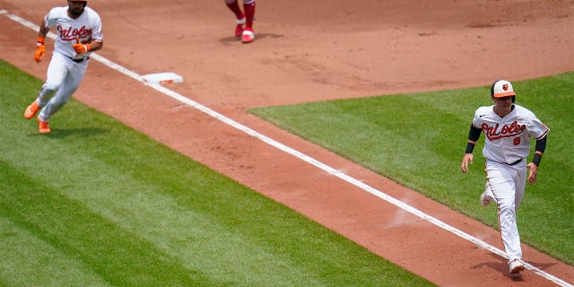 Baltimore Orioles' Ryan Mountcastle (6) runs home with teammate Anthony Santander (25) behind him as they both score on a single by Ramon Urias during the fourth inning of a baseball game against the Los Angeles Angels, Sunday, July 10, 2022, in Baltimore.