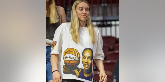 Connecticut Huskies guard Paige Bueckers looks on while wearing a shirt emblazoned with a graphic of Brittney Griner holding a "We Are BG" basketball, following the WNBA game between the Seattle Storm and the Connecticut Sun on June 17,2022, at Mohegan Sun Arena in Uncasville, CT. The Sun defeated the Storm 82-71. 