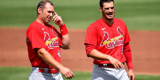 Paul Goldschmidt, #46, and Nolan Arenado, #28 of the St. Louis Cardinals, wait for their hat and gloves in between the second inning against the St. Louis Cardinals in a spring training game at Roger Dean Chevrolet Stadium on March 02, 2021 in Jupiter, Florida.