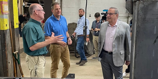 Former Maine governor and 2022 GOP gubernatorial nominee Paul LePage (right) and GOP Gov. Chris Sununu of New Hampshire (center) get a tour of Messer Truck Equipment in Westbrook, Maine on July 13, 2022