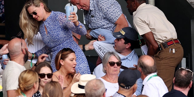 Security personnel and spectators remove a protester from the stands during the men's singles final match between Novak Djokovic and Nick Kyrgios at Wimbledon on July 10, 2022 in London.