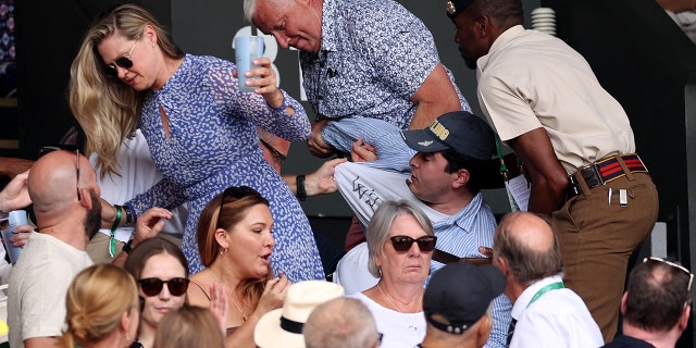 Security staff and spectators remove a protester from the stands during the men's singles final match between Novak Djokovic and Nick Kyrgios at Wimbledon on July 10, 2022, in London.