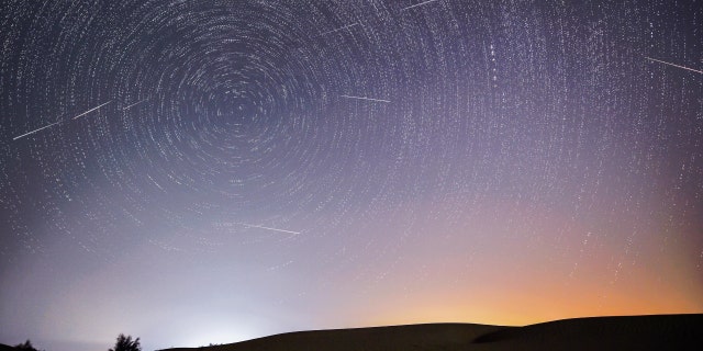 Photomontage pris le 13 août 2021 montrant le ciel nocturne pendant la pluie de météores perséides au-dessus d'une zone de démonstration écologique d'Engebei dans le désert de Kubuqi, dans la région autonome de Mongolie intérieure (nord de la Chine). 