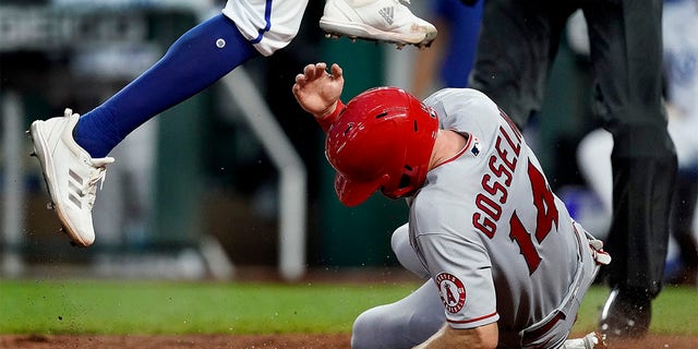 Kansas City Royals relief pitcher Amir Garrett leaps over Los Angeles Angels' Phil Gosselin (14) after Gosselin scored on Garrett's wild pitch during the fifth inning of a baseball game Tuesday, July 26, 2022, in Kansas City, Mo. 