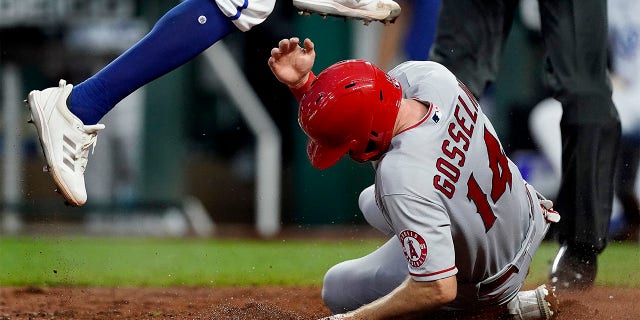Kansas City Royals relief pitcher Amir Garrett leaps over Los Angeles Angels' Phil Gosselin (14) after Gosselin scored on Garrett's wild pitch during the fifth inning of a baseball game Tuesday, July 26, 2022, in Kansas City, Mo.