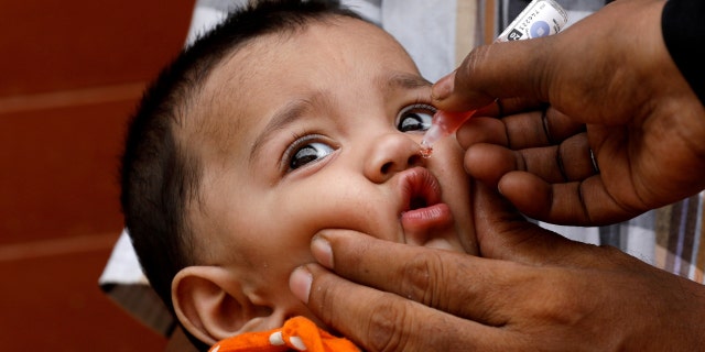 A young child receives polio vaccine drops during an anti-polio campaign in a low-income neighborhood in Karachi, Pakistan, on July 20, 2020. 