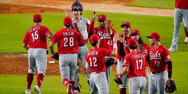 Cincinnati Reds' Kyle Farmer (17), Tyler Naquin (12) and Brandon Drury (22) celebrate with teammates after a baseball game against the New York Yankees on Tuesday, July 12, 2022, in New York. The Reds won 4-3. 