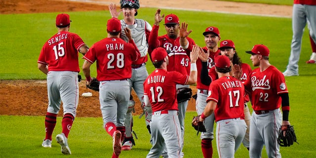 Cincinnati Reds' Kyle Farmer (17), Tyler Naquin (12) and Brandon Drury (22) celebrate with teammates after a baseball game against the New York Yankees on Tuesday, July 12, 2022, in New York. The Reds won 4-3.