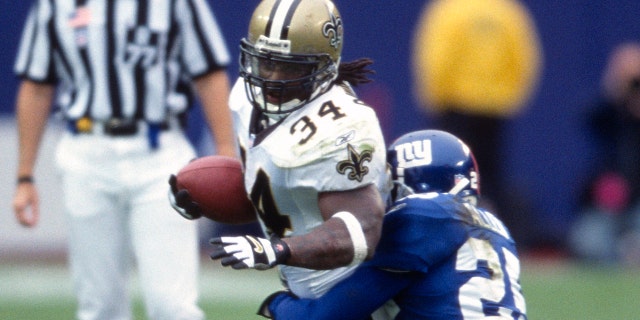Ricky Williams, #34 of the New Orleans Saints, carries the ball and gets tackled by Will Allen, #25 of the New York Giants, during an NFL football game September 30, 2001 at Giants Stadium in East Rutherford, New Jersey. Williams played for the Saints from 1999-2001.