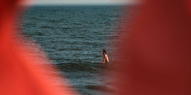 A surfer sits in the water on a warm evening at Rockaway Beach on July 19, 2022 in New York City. 