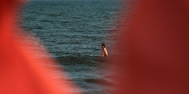 A surfer sits in the water on a warm evening at Rockaway Beach on July 19, 2022 in New York City.