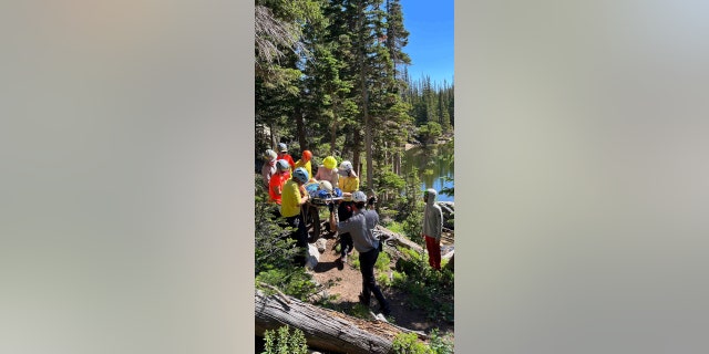 RMNP Search and Rescue Team members carrying a female patient in litter to waiting air ambulance at Odessa Lake