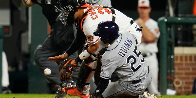 Tampa Bay Rays' Roman Quinn (25) scores a run as Baltimore Orioles catcher Robinson Chirinos waits for the throw on a two-run bases loaded double by Randy Arozarena during the 10th inning of a baseball game, Wednesday, July 27, 2022, in Baltimore. The Rays won 6-4 in ten innings. Rays' Taylor Walls also scored on the play.