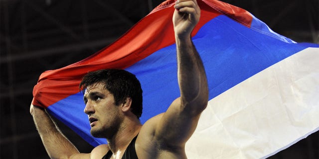 Russia's Shirvani Muradov celebrates with his national flag afte rwinning the gold medal at the men's freestyle 96kg final wrestling match against Kazakhstan's Taimuraz Tigiyev on August 21, 2008 at the 2008 Beijing Olympic Games.