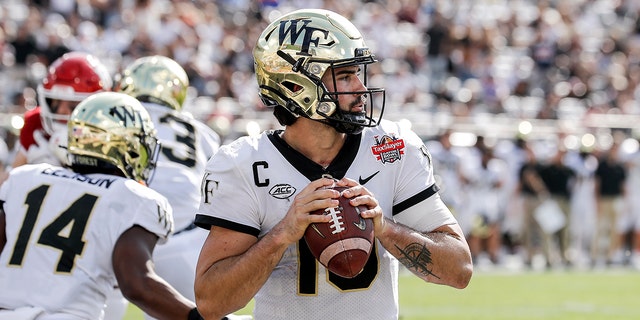 Quarterback Sam Hartman, #10 of the Wake Forest Demon Deacons, on a pass play in the end zone during the game against the Rutgers Scarlet Knights at the 77th annual TaxSlayer Gator Bowl at TIAA Bank Field on December 31, 2021 in Jacksonville, Florida.