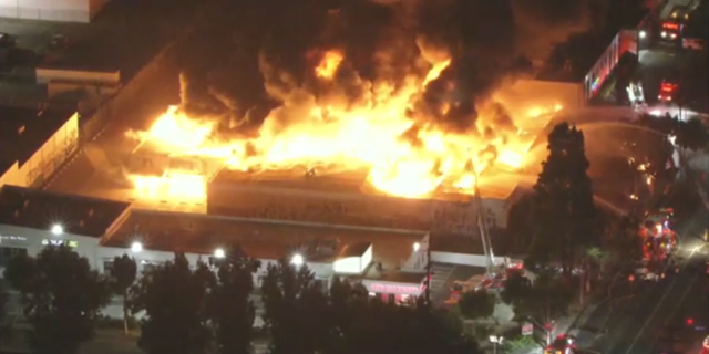 Fire shoots through the roof of a warehouse in Los Angeles, California.