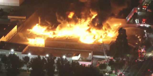 Fire shoots through the roof of a warehouse in Los Angeles, California.