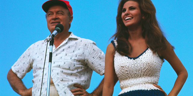 Comedian Bob Hope and actress Raquel Welch entertain American troops at an unidentified outdoor site in Vietnam, circa 1967.