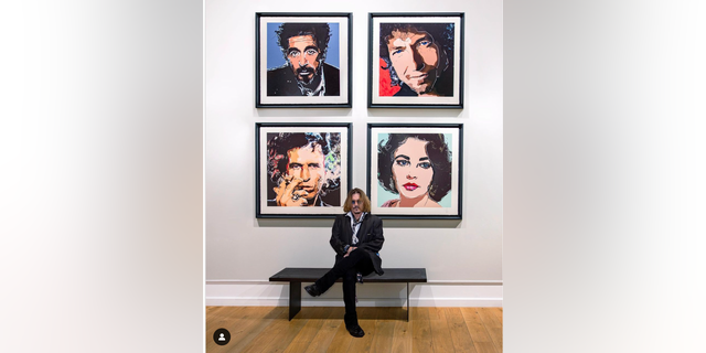 Johnny Depp poses under his artwork featuring portraits of Keith Richards, Elizabeth Taylor, Al Pacino and Bob Dylan at the Castle Fine Art gallery in London.