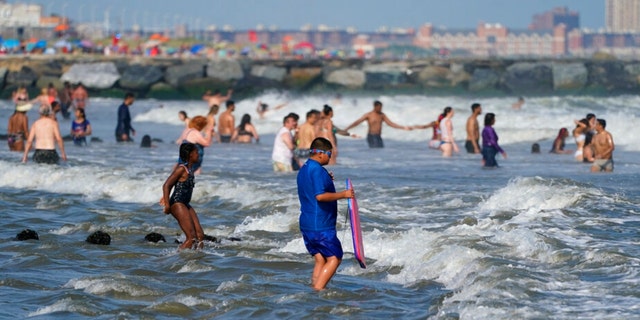 People enjoy the water at Rockaway Beach, Tuesday, July 19, 2022, in the Queens borough of New York.