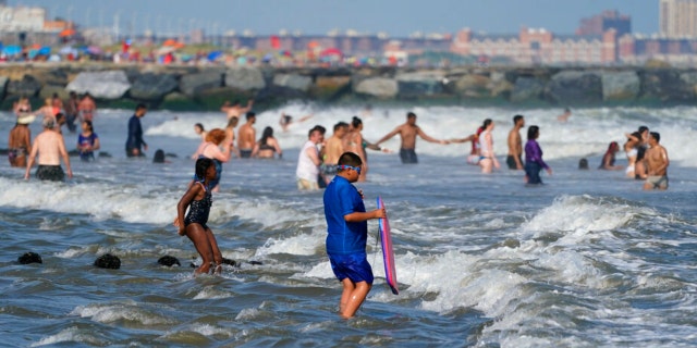 People enjoy the water at Rockaway Beach, Tuesday, July 19, 2022, in the Queens borough of New York. 