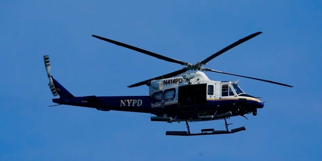 A New York Police Department helicopter patrols the shoreline at Rockaway Beach, Tuesday, July 19, 2022, in the Queens borough of New York.