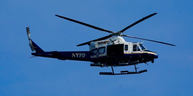 A New York Police Department helicopter patrols the shoreline at Rockaway Beach, Tuesday, July 19, 2022, in the Queens borough of New York. 