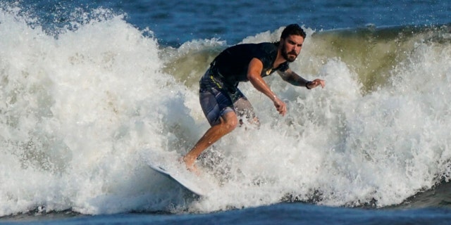 A man surfs at Rockaway Beach, Tuesday, July 19, 2022, in the Queens borough of New York.