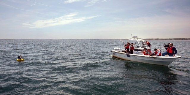 University of New England students and media take photos of a buoy after it was deployed in the water of Saco Bay. The buoy picks up a signal if a tagged white shark is nearby and can send a real-time notification to researchers and lifeguard directors to alert them to the presence of a shark.