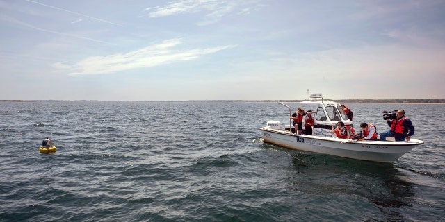 University of New England students and media take photos of a buoy after it was deployed in the water of Saco Bay. The buoy picks up a signal if a tagged white shark is nearby and can send a real-time notification to researchers and lifeguard directors to alert them to the presence of a shark.