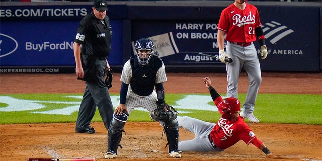 Cincinnati Reds' Brandon Drury (22) watches as Donovan Solano (7) slides past New York Yankees catcher Jose Trevino to score on a single by Jonathan India during the ninth inning of a baseball game Tuesday, July 12, 2022, in New York. The Reds won 4-3. 