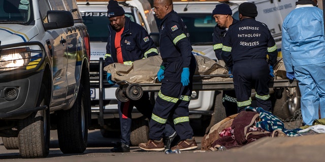 A body is removed from the scene of an overnight bar shooting in Soweto, South Africa, Sunday July 10, 2022. A mass shooting at a tavern in Johannesburg's Soweto township has killed 15 people.