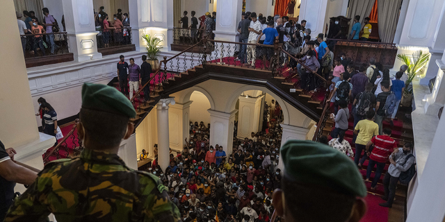 육군 장교들이 7월 11일 스리랑카 콜롬보에서 습격을 받은 고타바야 라자팍사 대통령의 관저가 습격당한 지 이틀 만에 사람들을 지켜보고 있다.